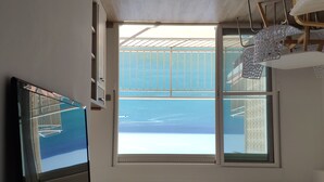 Una habitación moderna con un ventanal grande, un televisor de pantalla plana y un ventilador de techo.
