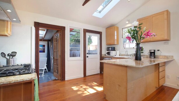 A modern kitchen with a central island, wooden cabinets, and a skylight. - Curtis Cottage · Berkeley Cottage, comfy, stylish, good wifi (Berkeley)