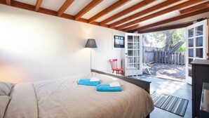 A bedroom with a bed, a lamp, and a view of the backyard through an open door. - Curtis Cottage · Berkeley Cottage, comfy, stylish, good wifi (Berkeley)