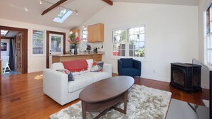 A spacious living room with a white sofa, a coffee table, and a fireplace. - Curtis Cottage · Berkeley Cottage, comfy, stylish, good wifi (Berkeley)
