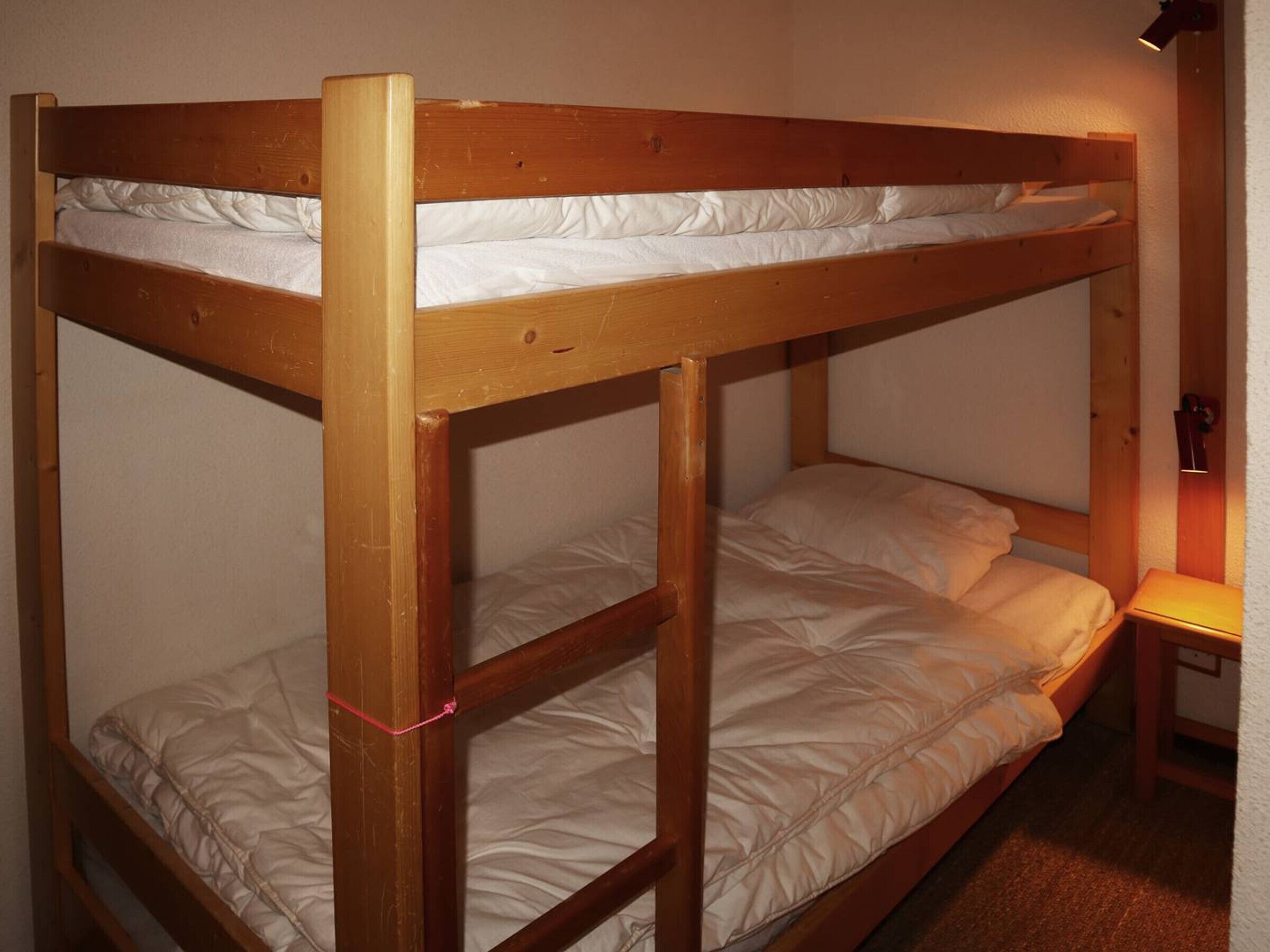 A bunk bed with two levels, each with a mattress and pillows.