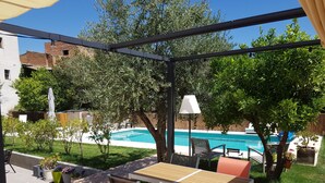 A patio area with a table and chairs, a pool, and surrounding greenery. - Casa Los Tejones (El Pinar)