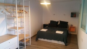 A bedroom with a bed, a wardrobe, a nightstand, and a shelf with books. - Casa Los Tejones (El Pinar)