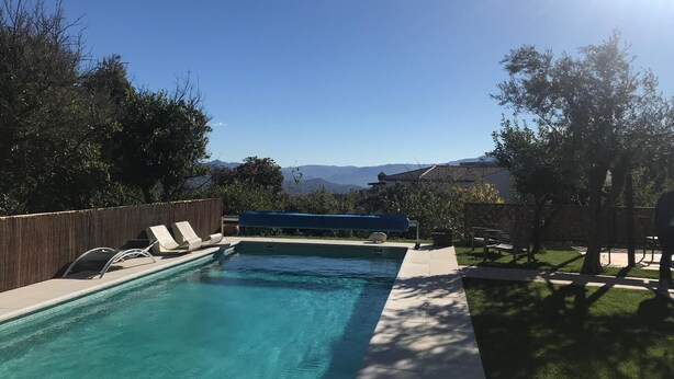 A rectangular swimming pool with a wooden fence and lounge chairs. - Casa Los Tejones (El Pinar)