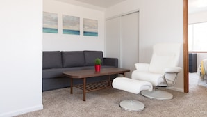 A modern living room with a grey sofa, a white armchair, a wooden coffee table, and a small potted plant. - Large House on a Hill- 15 Min Walk 2 Bart (Richmond)