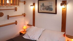 A bed with white bedding, a clock, and a painting on the wall. - 2P6 Apartment in Les Orres, central location, valley view (Les Orres)