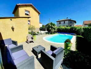 A pool area with outdoor furniture and a yellow building. - Aux Deux Lots (Sorbiers)