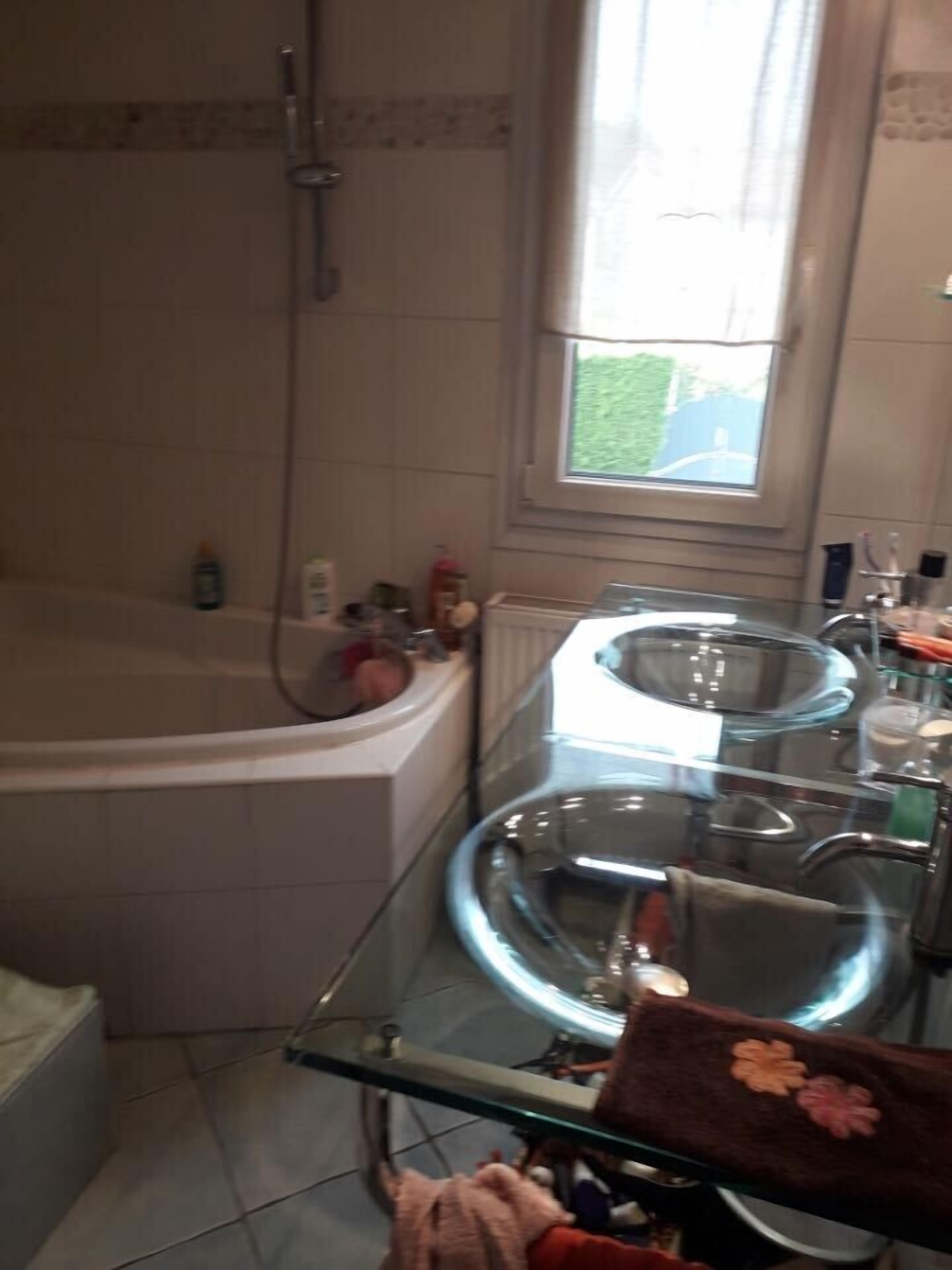 Un baño con bañera, cabina de ducha de vidrio y ventana que proporciona luz natural.