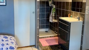 Un baño pequeño con ducha, lavamanos e inodoro.