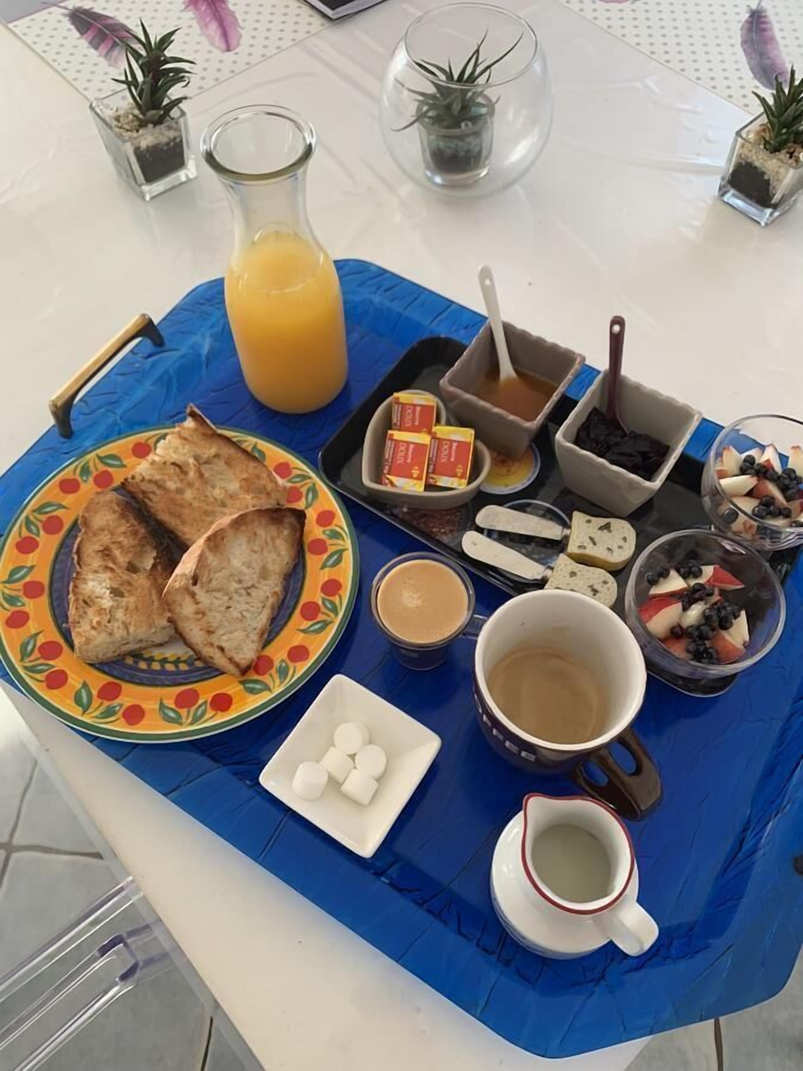 A breakfast tray with toast, fruit, coffee, and juice.