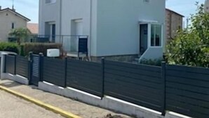 Un edificio residencial de dos plantas con techo plano y un balcón en el piso superior.