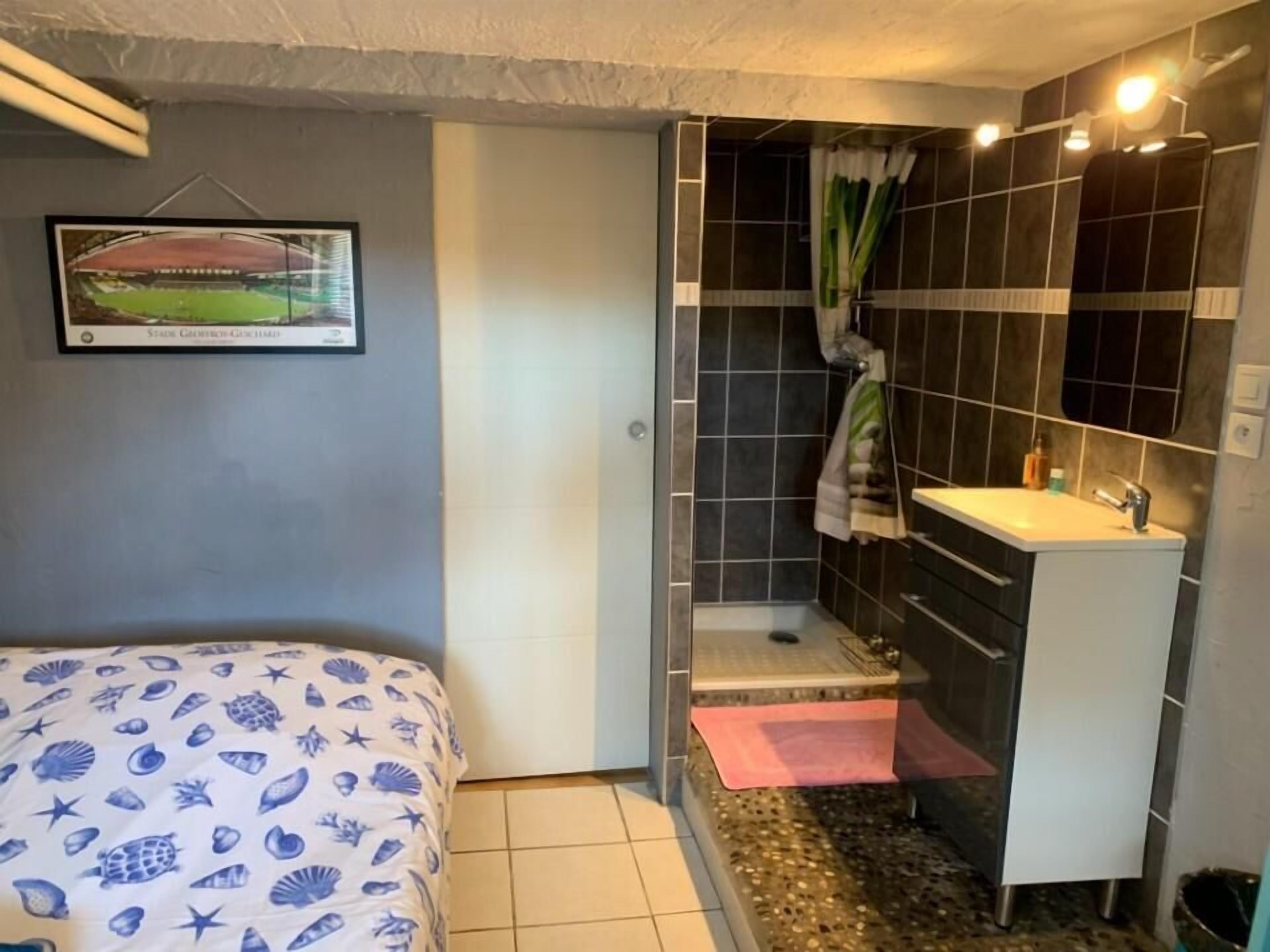 Ein kleines Hotelzimmer mit Bett, einem Bad mit Dusche und einem Waschbecken.