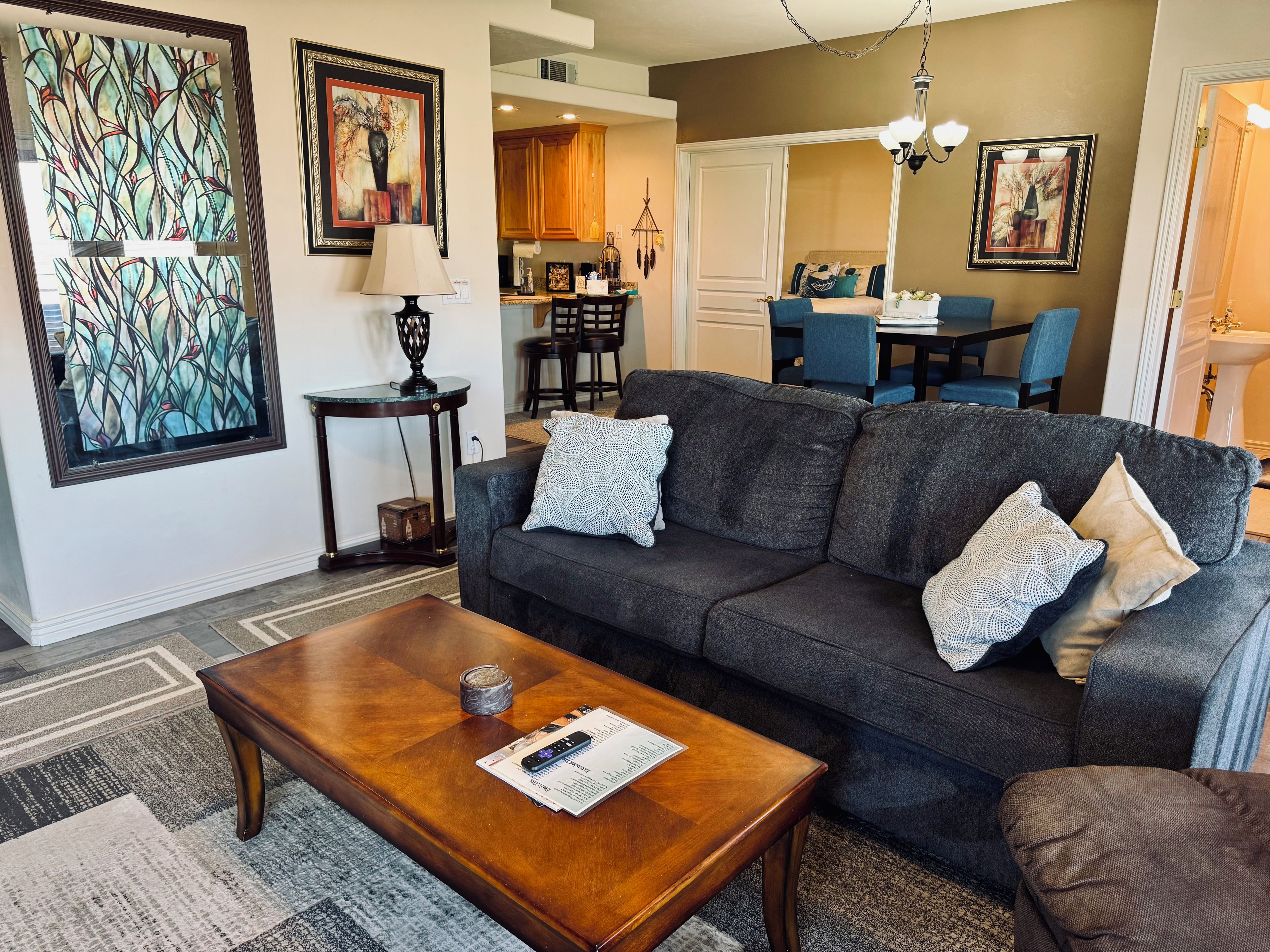 A living room with a dark grey sofa, a wooden coffee table, and a patterned rug.
