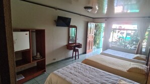 A hotel room with two beds, a desk, a chair, a TV, and a window with a view of the outside. - Hotel FAS & OFF Site Thermal Resort (La Fortuna)