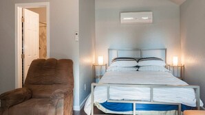 A bedroom with a bed, a chair, and an air conditioning unit. - Spotless Back House (Fresno)