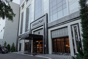 Un hotel Sheraton con fachada moderna, ventanas amplias y una entrada destacada.