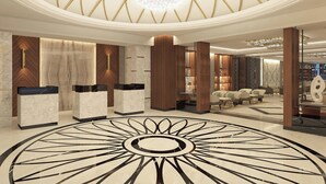A lobby with a circular floor design, marble reception desks, and a chandelier. - Sheraton Bishkek (Bishkek)