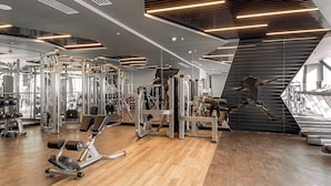 A modern gym with various exercise equipment, large mirrors, and a wooden floor. - Sheraton Bishkek (Bishkek)
