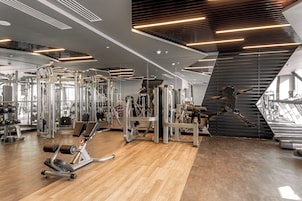 Un gimnasio moderno con diverso equipo de ejercicio, espejos amplios y suelo de madera.