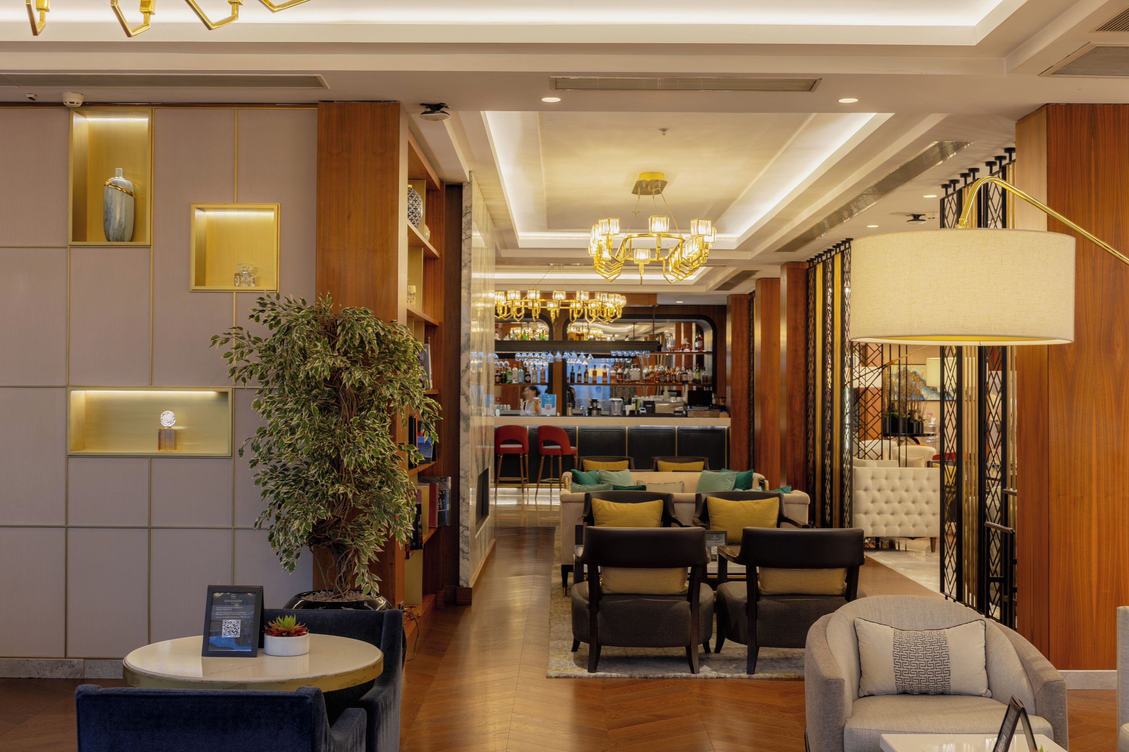 A hotel lobby with a bar area, seating, and a large plant.