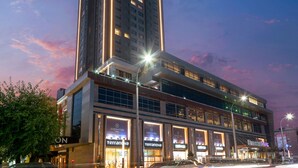 A Sheraton hotel with multiple floors, large windows, and illuminated signage. - Sheraton Bishkek (Bishkek)