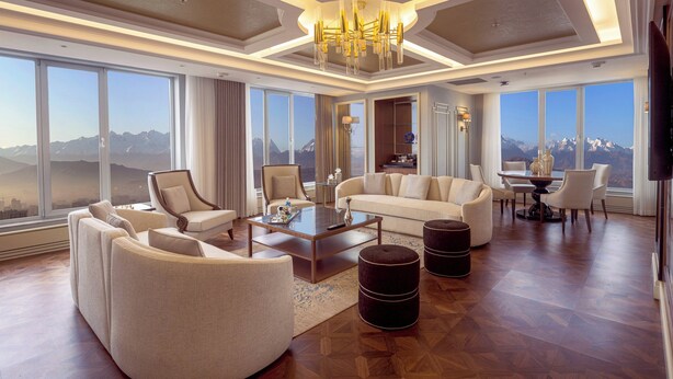 A spacious living room with a large window offering a mountain view, a chandelier, and a modern coffee table. - Sheraton Bishkek (Bishkek)