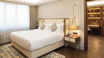 A hotel room with a large bed, a bedside table with a lamp, a desk, and a mirror.