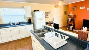 A compact kitchen with white cabinets, a sink, a refrigerator, and a countertop with a dish rack. - Perfect for two on the River at Mel Fishers Museum  (Sebastian)