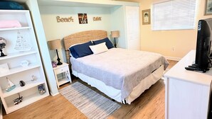 A bedroom with a bed, bedside tables, a desk, a lamp, a shelf with decorative items, and a window with blinds. - Perfect for two on the River at Mel Fishers Museum  (Sebastian)