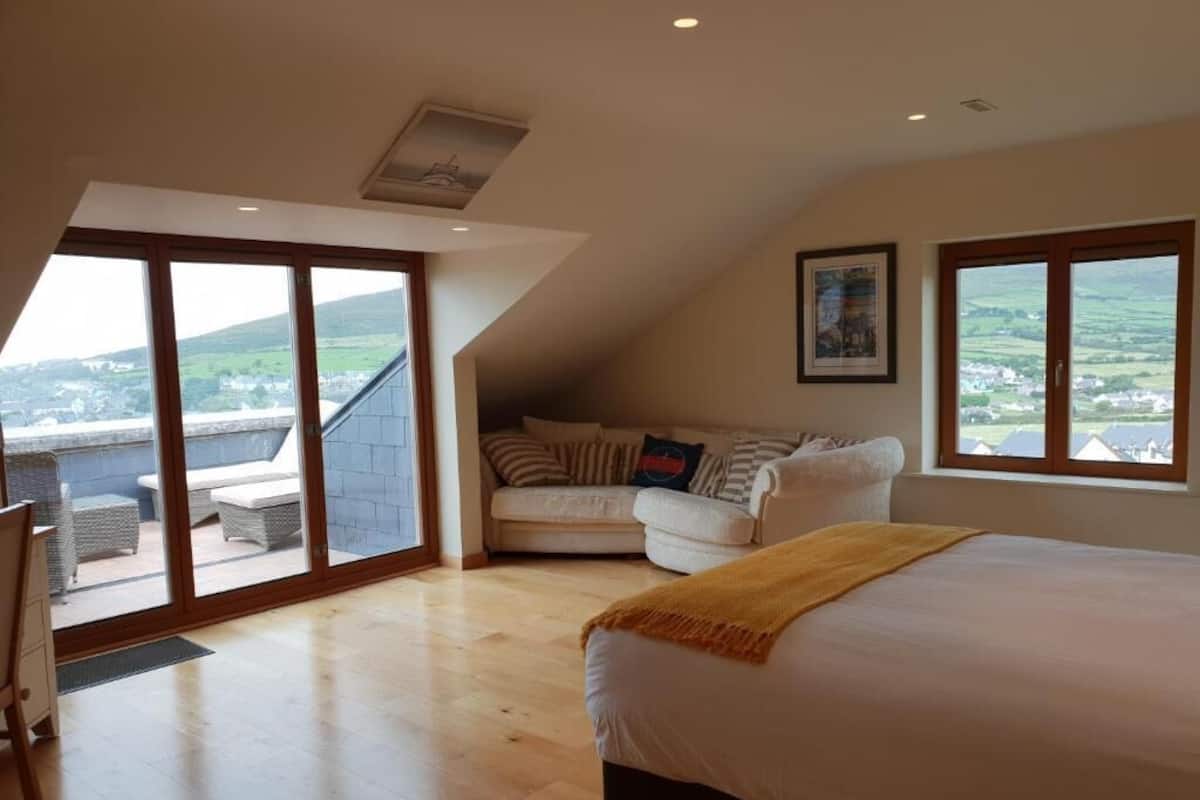 Quarto com uma cama grande, um sofá e uma varanda com vista para o campo.
