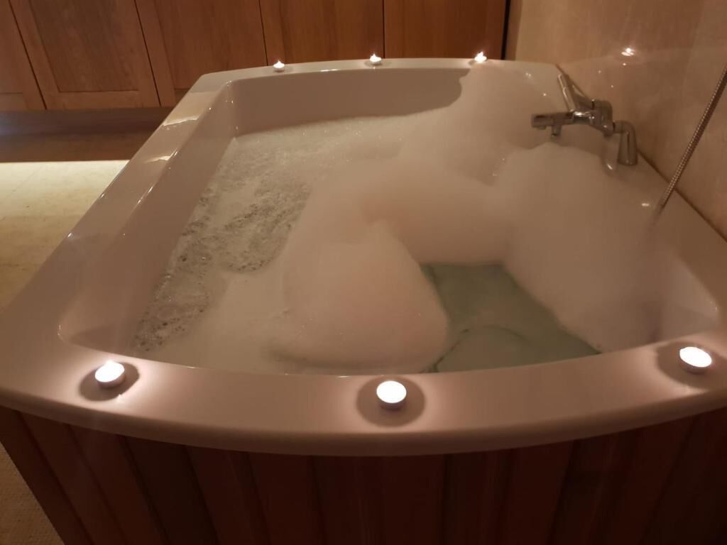 Een badkuip vol bubbels, een kraan en een lamp.