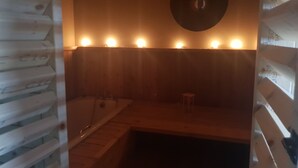 A wooden cabin interior with a wooden bench, a round table, and a bathtub. - Fab View (Dingle)