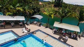 Una piscina al aire libre, sombrillas, sillones reclinables de piscina