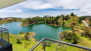 A panoramic view of a lake surrounded by hills and greenery, with a clear sky above. - Hotel Verony Guatape (Guatapé)