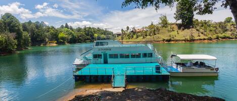 A ferry docked at a calm river with a dock extending into the water.