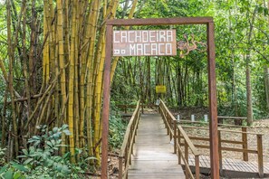 Un puente de madera que conduce a un letrero que dice "Cachoeira do Macaco" en una zona boscosa.