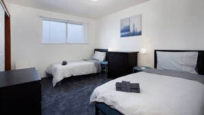 A hotel room with two single beds, a dark wooden dresser, a desk, and a window with blinds. - Convenient 2 bedroom, walk to Bart, 10 min to Berkeley (Richmond)