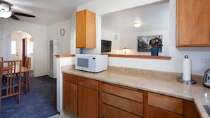 A kitchen with wooden cabinets, a microwave, and a dining area with chairs. - Convenient 2 bedroom, walk to Bart, 10 min to Berkeley (Richmond)