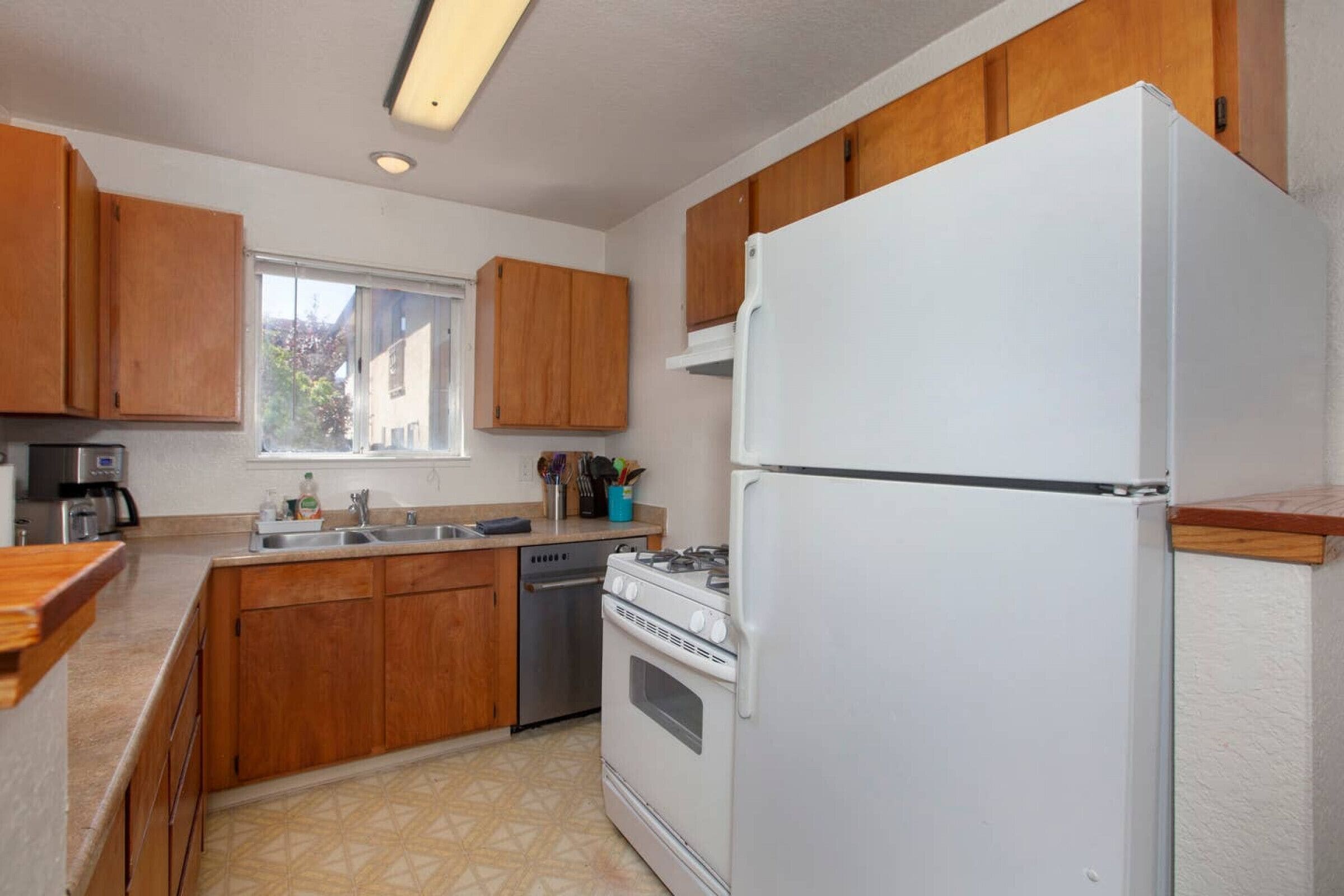 Une cuisine avec des meubles de rangement en bois, un réfrigérateur blanc, une cuisinière et un lave-vaisselle.
