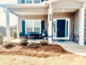Welcome to this charming home, featuring a cozy front porch with a bench and mailbox, surrounded by a beautifully landscaped garden.