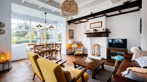 Un salón luminoso con un ventanal grande, muebles de madera, un televisor y una chimenea.