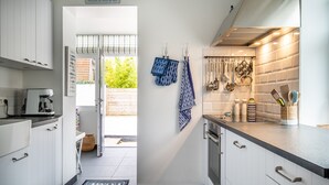 Una cocina moderna con armarios blancos, una cafetera y un tendedero con utensilios.