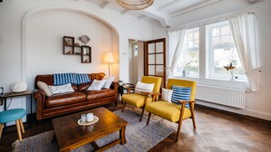 Una sala de estar acogedora con un sofá de cuero marrón, un sillón amarillo y una mesa de centro de madera.