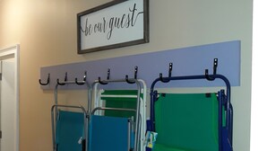 A wall-mounted rack with multiple bags and a sign above it. - Super cute and clean studio (Myrtle Beach)
