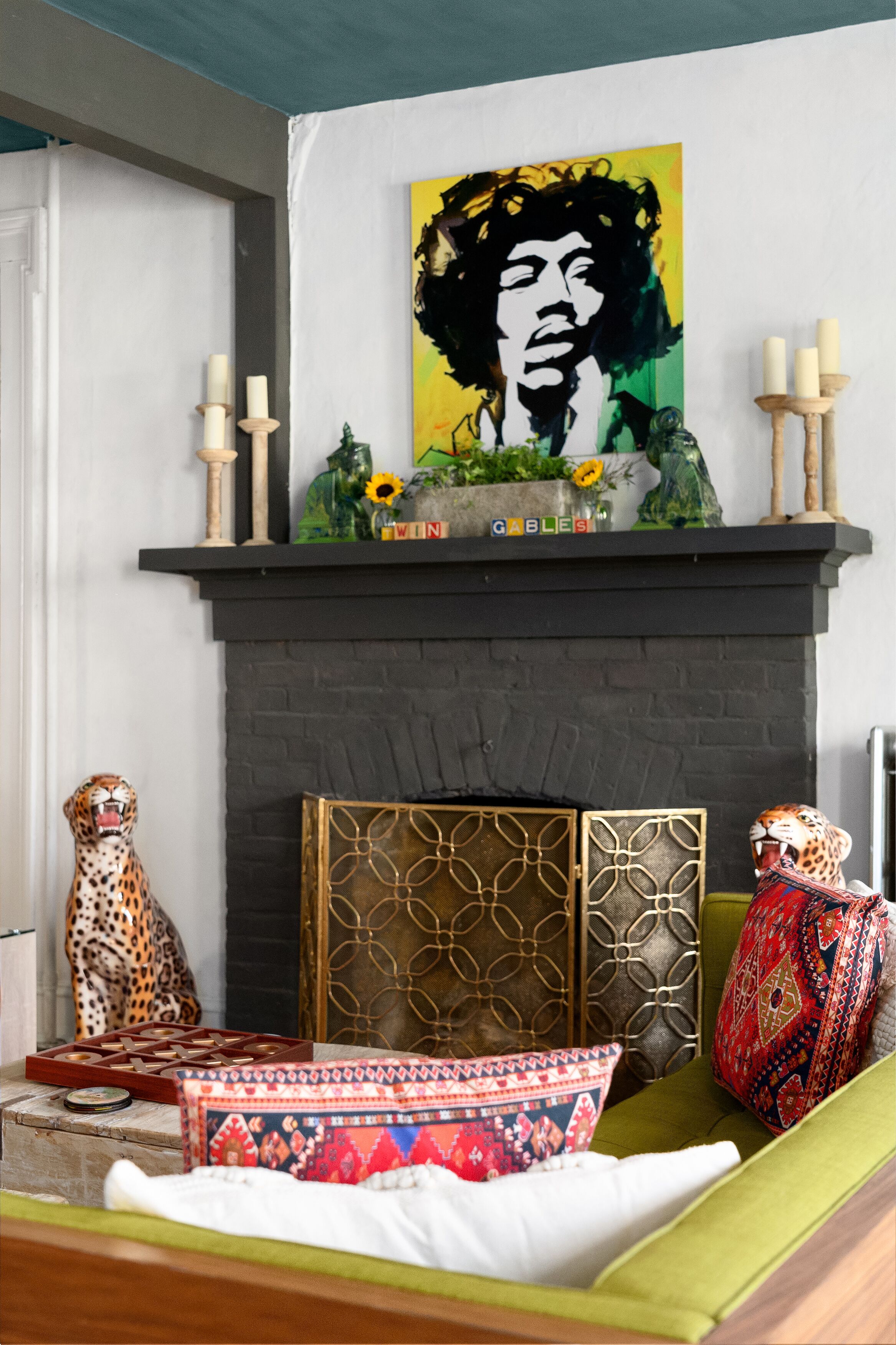 Una sala de estar con chimenea, un cuadro encima y elementos decorativos como una figura de leopardo y cojines estampados.