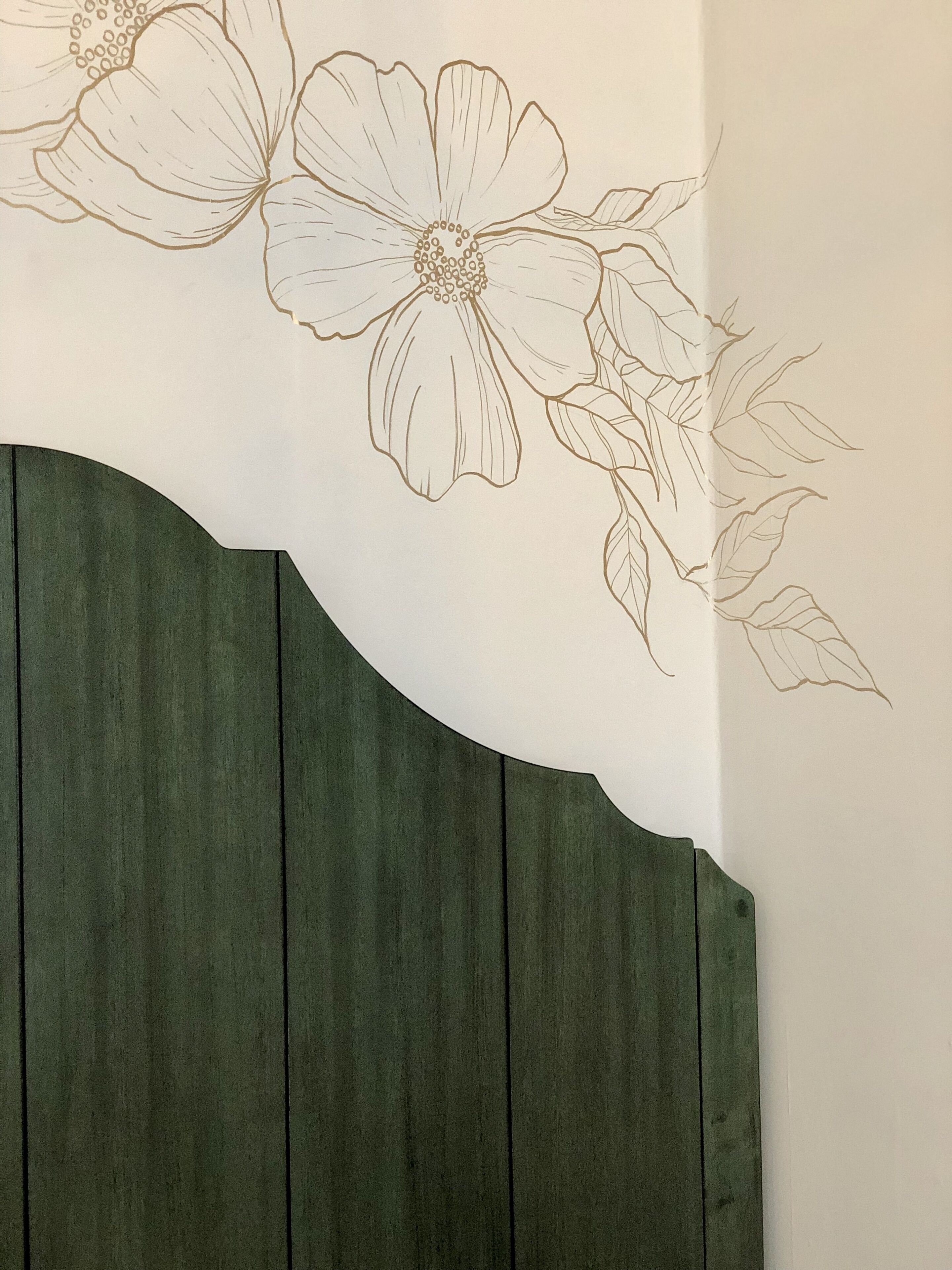 A wall with a floral design and a wooden panel.