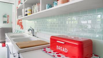 Una cocina con mostrador blanco, panera roja y salpicadero de azulejos.