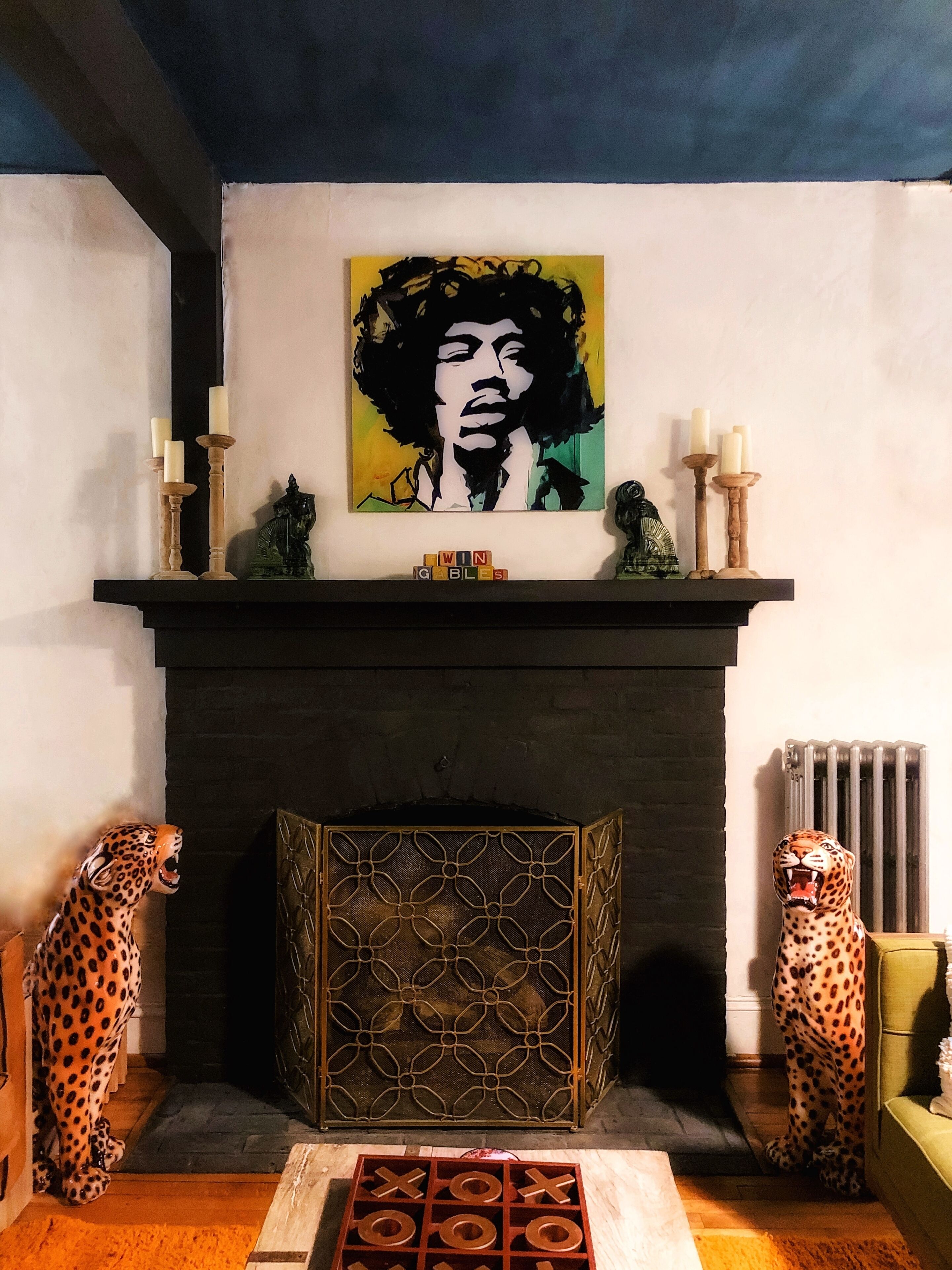 Una chimenea de diseño moderno, flanqueada por estatuas de leopardo y una obra de arte vibrante en la parte superior.