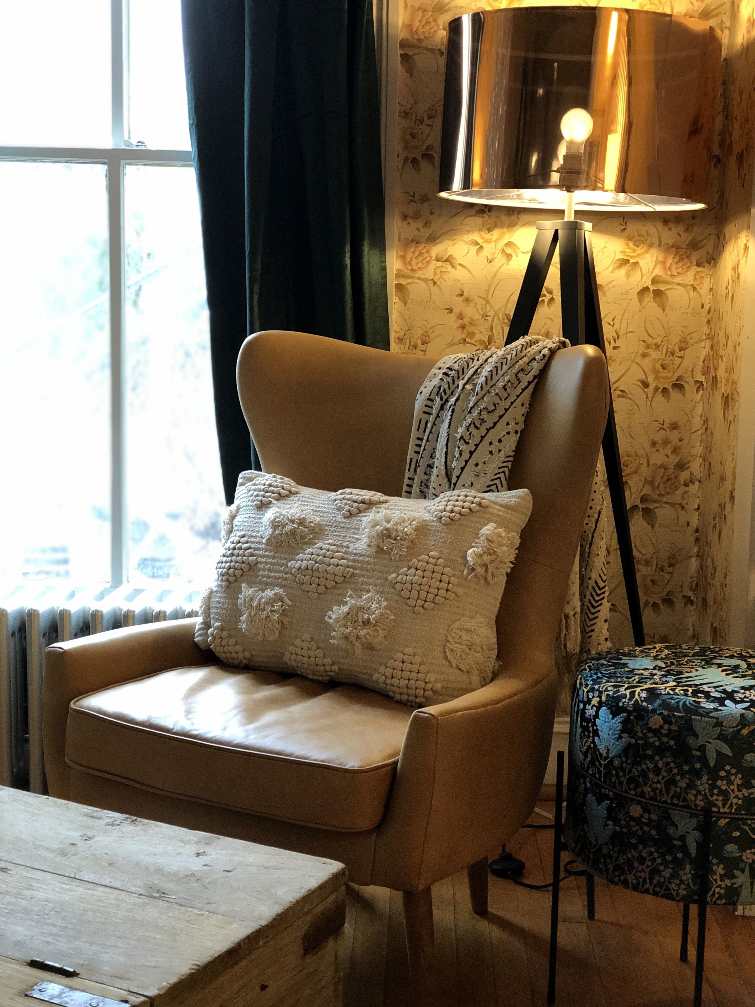 Une pièce chaleureuse avec un fauteuil en cuir, un coussin décoratif à motifs, une petite table et une lampe.