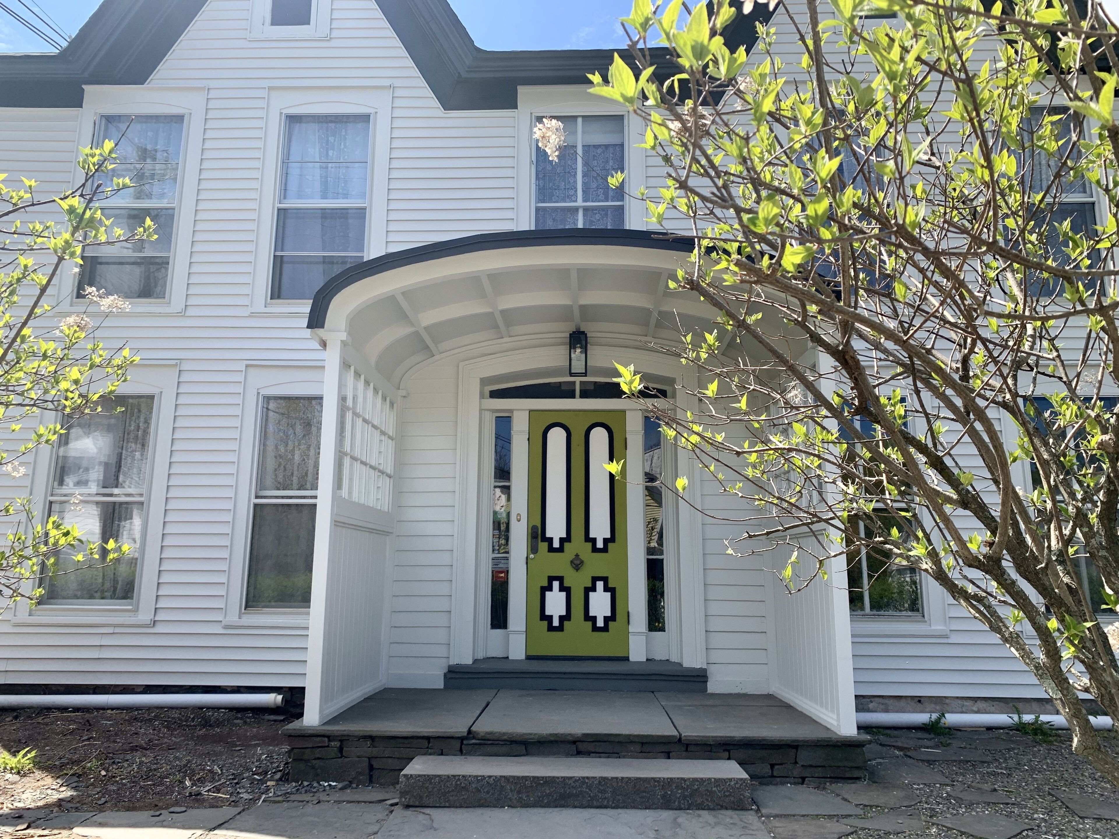 A two-story house with a green door and a porch.